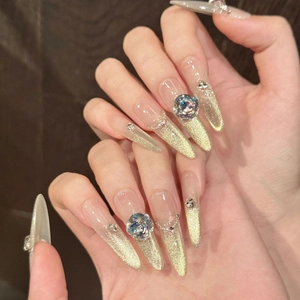 Nude stiletto press-on nails with golden cat-eye gradient and 3D rhinestones