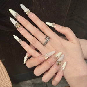 Faux ongles blanc crème avec nœuds 3D, perles et cristaux de forme stiletto longue