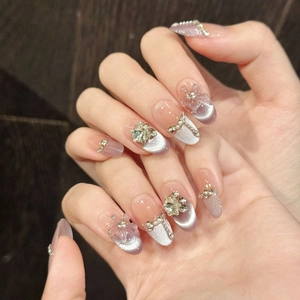 Purple cat eye press-on nails with 3D flowers, pearls, and crystals in almond shape