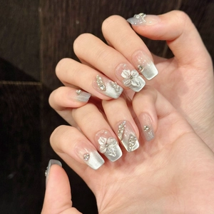 Silver cat eye press-on nails with 3D white flowers, pearls and rhinestones on wood