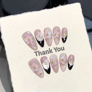Close-up of pink handmade press-on nails with 3D floral accents and French cat-eye design
