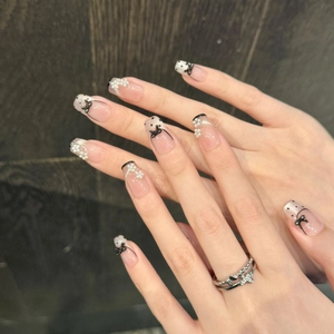 French ballerina press-on nails with black dots, white pearls, and bows on nude base