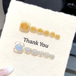 Detail of blue and orange handmade press-on toe nails with polka dots and cat-eye effect