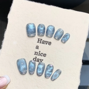 Macro detail of ice blue cat-eye handmade press-on nails with silver shimmer finish