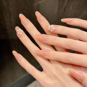 Handmade 3D white floral press-on nails with pearls and crystals on almond nude gradient