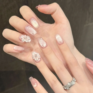 Pink cat eye press-on nails with 3D floral accents and elegant rhinestone embellishments