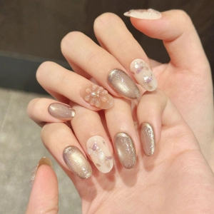 Cat-eye press-on nails with 3D floral relief and pearl accents in cream gold