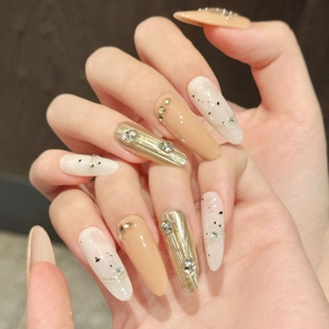 Macro shot of handmade almond nails with gradient brown, butterfly gems and gold leaf
