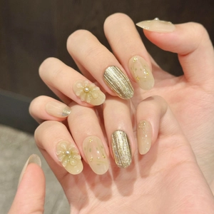 Champagne press-on nails with gold foil and 3D floral accents in oval shape