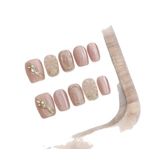 Pink cat-eye press-on nails with 3D floral relief and gold accents on white background