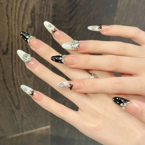 Press-on nails featuring black bows, glitter accents and rhinestones on almond shape