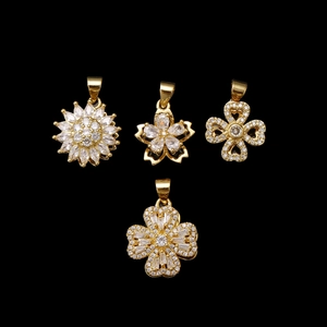 Rotating gold-plated clover and flower pendants with sparkling cubic zirconia on black background