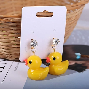 Detail of yellow duck earrings with rhinestones on a card over a lifestyle background
