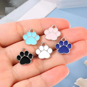Five colorful alloy paw print pendants held in palm for DIY necklace and bracelet jewelry