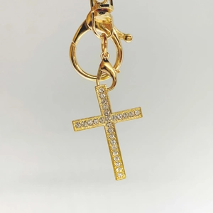 Macro shot of gold-tone cross pendant with sparkling rhinestones and lobster clasp detail