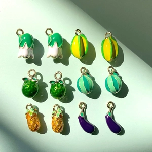 DIY colorful vegetable and fruit enamel charms with golden metal loops on green background
