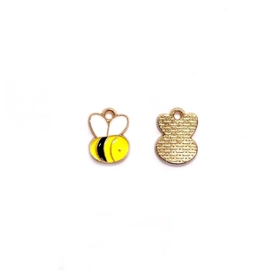 Detalle de colgantes de abeja esmaltados amarillos con textura de panal en el reverso