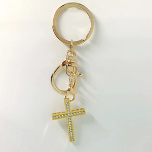 Golden cross keychain with sparkling zircons and swivel clasp on white background