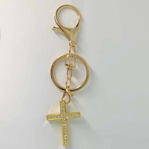Close-up of golden cross keychain pendant featuring sparkling inlaid rhinestones