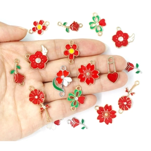 Enameled flower and heart pendants in red and green with gold plating held in hand