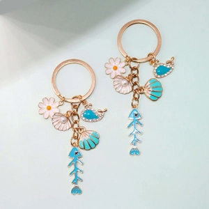 Detailed view of sea-themed charms including shell, whale, and flower on a gold keychain