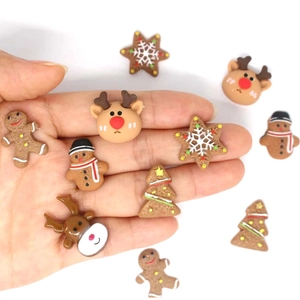Mano sosteniendo dijes navideños de resina con hombre de jengibre y reno para manualidades