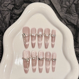 Cat eye press-on nails with pearls, crystals, and rose art on a ceramic tray