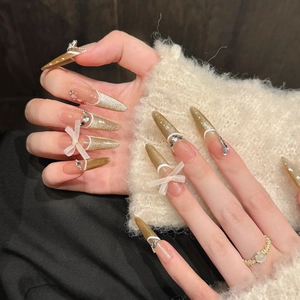 Champagne gold cat-eye press-on nails with 3D bows and rhinestone embellishments