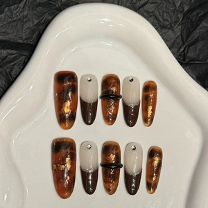 Handmade press-on nails set in amber brown with gold foil accents and French tips