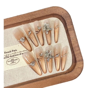 Golden amber cat-eye press-on nails with luxury rhinestones and metal butterfly charms