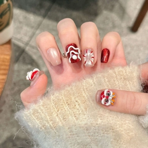 Handmade red press-on nails with 3D lion dance motif and cat-eye finish on a hand