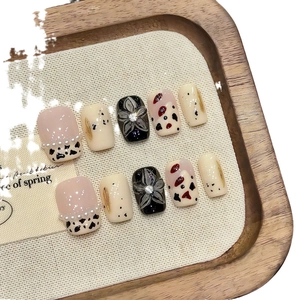 Faux ongles French avec imprimé vache, fleurs 3D noires et détails en perles