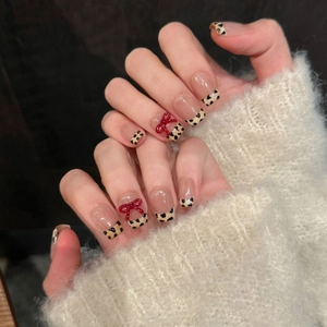 Handmade leopard print French press-on nails with 3D red bow on a textured background