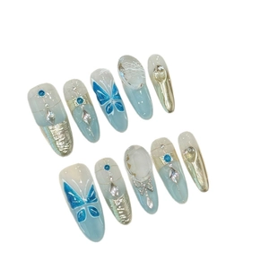 Icy blue gradient press-on nails with butterfly designs, pearls, and crystals stiletto shape