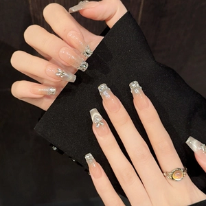 Long coffin press-on nails with nude pink gradient, silver glitter, and 3D crystal bows
