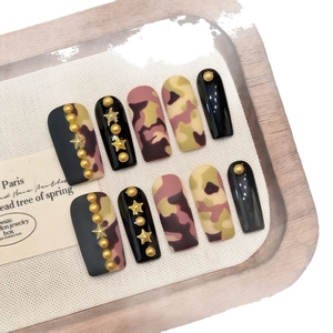 Faux ongles à presser motifs camouflage et étoiles dorées sur plateau bois