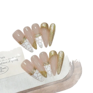 Handmade stiletto press-on nails with nude base, white cracks, and gold metal accents