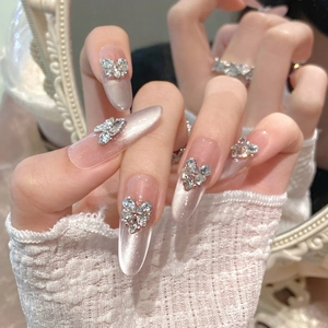 Handmade almond press-on nails with cat eye finish and sparkly rhinestone bows