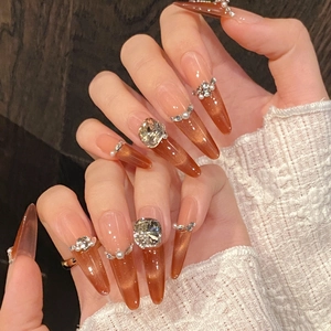 Brown cat-eye press-on nails with pearls and rhinestones on lace background