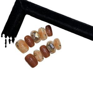 Handmade press-on nails with marble caramel texture, gold foil, and crystal rhinestones