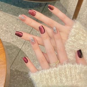 Handmade press-on nails with burgundy cat eye design and 3D rhinestone snowflakes
