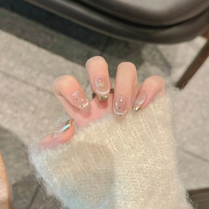 French cat-eye press-on nails with golden bows and nude glitter finish on cozy background