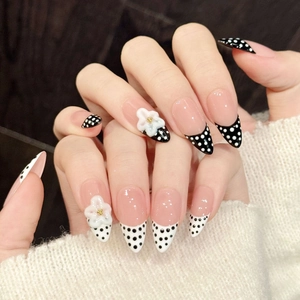 Faux ongles à pois roses et noirs avec fleurs 3D blanches sur forme amande