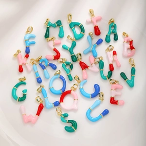 Macro shot of 26 colorful enamel alphabet pendants with gold plating for DIY jewelry