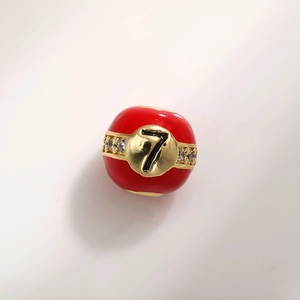 Macro shot of 12mm red enamel charm bead with gold band, sparkling stones and number 7
