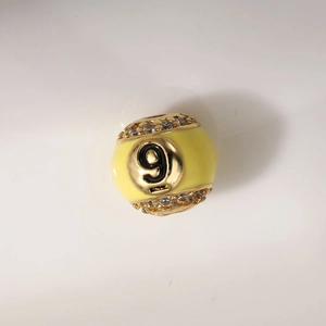 Detail of 12mm gold plated bead with yellow enamel and a sparkling number 9 crystal charm