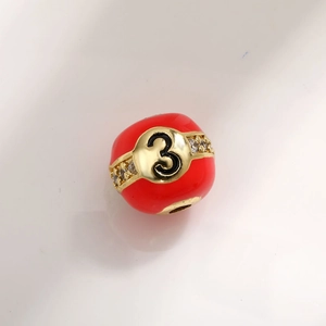 Macro shot of red enamel number 3 charm bead with gold plating and zircon inlay