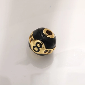 Macro detail of number 8 billiard ball charm with gold plating and zircon inlay