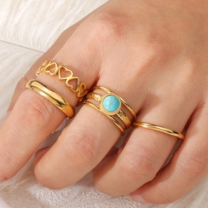 Lot de quatre bagues en acier doré avec pierre turquoise et motif de cœur ajouré