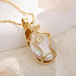 Macro shot of baroque pearl pendant wrapped in gold wire with zircon ginkgo leaf detail